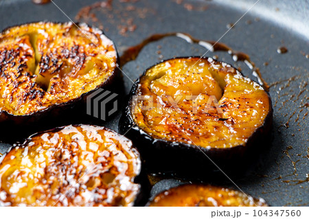 茄子(なす)を輪切りにしてフライパンで焼く調理シーン(たれ焼き)。 104347560