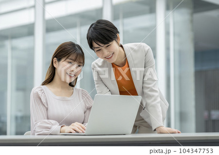パソコンの画面を見ながら話す2人のビジネスウーマン パソコンの画面を見ながら話す2人のビジネスウーマン 104347753