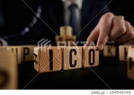 ICO symbol. Businessman hand turns wooden cubes ICO. ICO symbol. Businessman hand turns wooden cubes ICO. 104348749