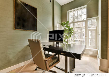 a home office with a desk and chair in front of a large painting on the wall behind it is a window 104349988