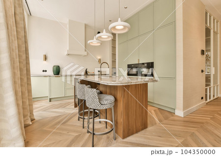 a modern kitchen with wood flooring and light green cabinets in the room is also decorated with white pendants a modern kitchen with wood flooring and light green cabinets in the room is also decorated with white pendants 104350000
