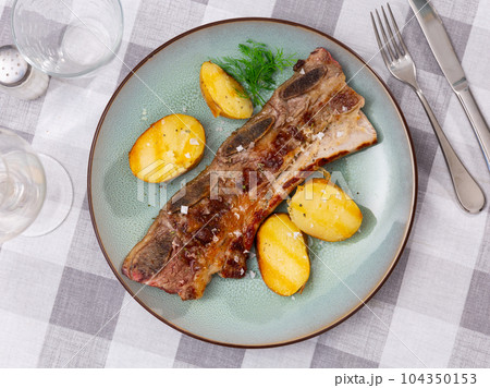 Grilled veal ribs churrasco with baked potatoes and greens 104350153