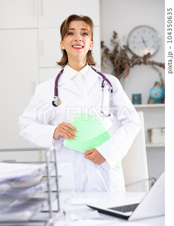 Woman doctor wear white medical uniform and stethoscope with folder of documents Woman doctor wear white medical uniform and stethoscope with folder of documents 104350635