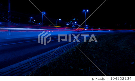 Lights of cars at night. Street line lights. Night highway city. Long exposure photograph night road. Colored bands of red light trails on the road. Background wallpaper defocused  104352134