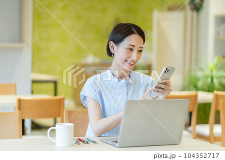 スマホを持った女性　コワーキングスペースで働く女性　働く女性 104352717