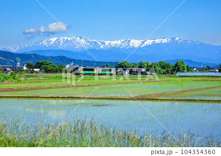 飯豊連峰を背景に会津盆地を走る只見線の列車キハE120形(福島県会津坂下町、5月下旬午前) 104354360