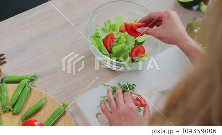 Top view of young girl in the process of preparing healthy food. Preparation of fresh vegetable salad. Healthy eating and cooking concept. 104359006