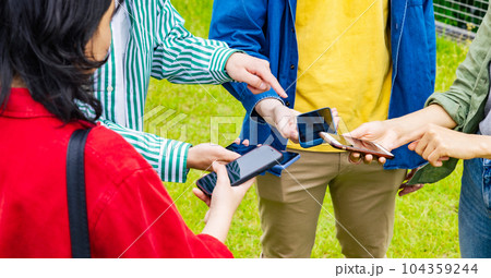 スマホを見せ合う多国籍若者グループ スマホを見せ合う多国籍若者グループ 104359244