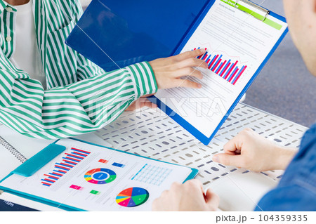 書類を見ながら会議する人々 104359335