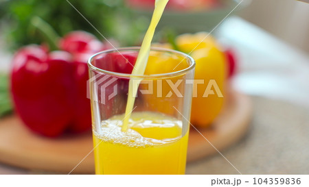 Person pouring fresh orange juice into a transparent glass in the modern kitchen. Organic vitamin drink. 104359836