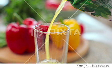Person pouring fresh orange juice into a transparent glass in the modern kitchen. Organic vitamin drink. 104359839
