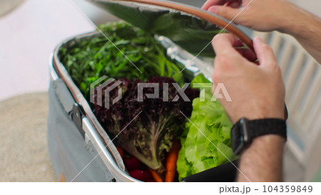 Man unpacking a bag with fresh vegetables in kitchen. Buy healthy organic vegetables. Man use food delivery service. Man unpacking a bag with fresh vegetables in kitchen. Buy healthy organic vegetables. Man use food delivery service. 104359849