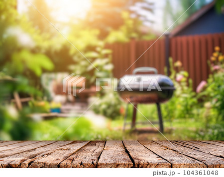 Summer time in backyard with wooden table, grill BBQ and blurred background Summer time in backyard with wooden table, grill BBQ and blurred background 104361048