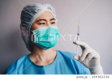 Healthcare worker looking a syringe before injection vaccine or medicine to patients. Syringes are frequently used in clinical medicine to administer injection into the bloodstream. 104362230