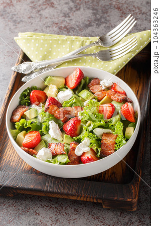 Delicious light salad of strawberries, avocado, bacon, lettuce, feta cheese close-up in a bowl. Vertical Delicious light salad of strawberries, avocado, bacon, lettuce, feta cheese close-up in a bowl. Vertical 104363246