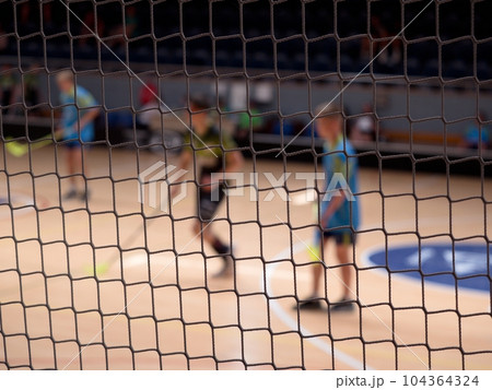 Pplayers of florball during match. View through the protective net Pplayers of florball during match. View through the protective net 104364324