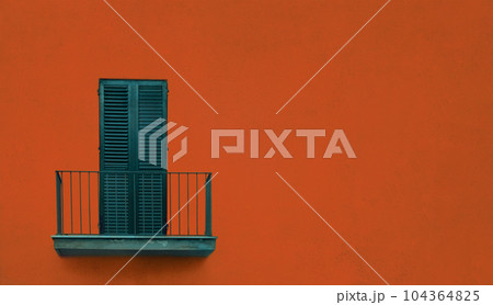 metallic green balcony with green wooden sash door with shutters on orange brown wall 104364825