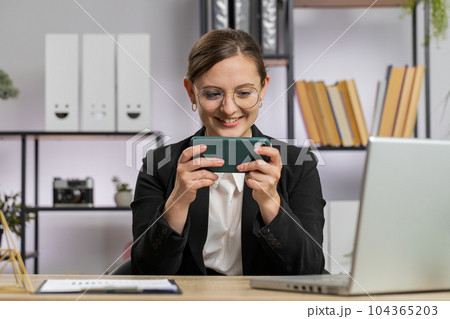 Business woman playing on smartphone exciting mobile application celebrate winning shooter game 104365203
