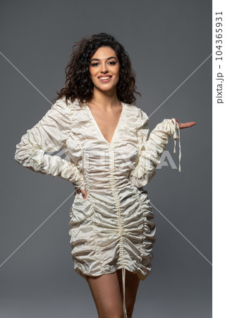 Smiling young brown-haired woman in white draped dress Smiling young brown-haired woman in white draped dress 104365931