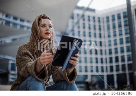 Portrait of young fashionable woman in a city with digital tablet. 104366396