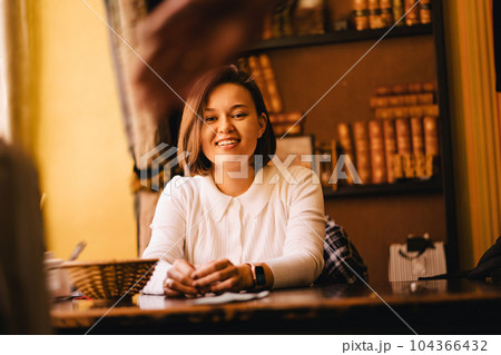 Attractive young brunette woman sitting at a table in the library. Attractive young brunette woman sitting at a table in the library. 104366432