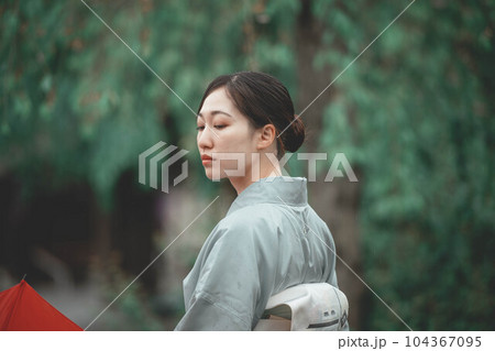 自然溢れる中で赤い傘をさす和服の若い女性 自然溢れる中で赤い傘をさす和服の若い女性 104367095