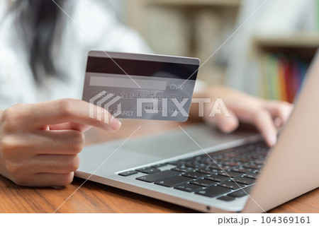 Hand holding credit card and using computer online for shopping or paying bills. Hand holding credit card and using computer online for shopping or paying bills. 104369161