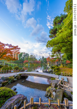 秋晴れの青空と紅葉が美しい兼六園霞ヶ池のことじ灯篭の風景 104370311