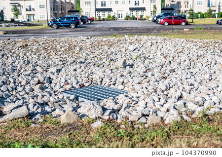 Grated storm drain inlet surrounded by rock for soil erosion control Grated storm drain inlet surrounded by rock for soil erosion control 104370990