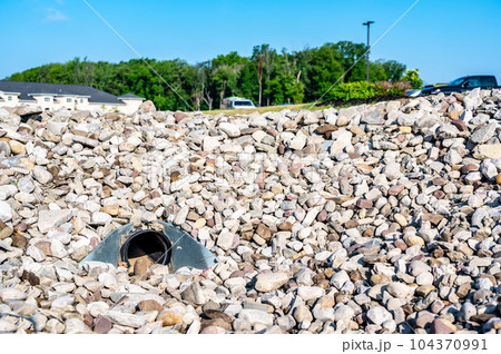 underground drainage storm drain with winged walls surrounded by rock for erosion control  104370991