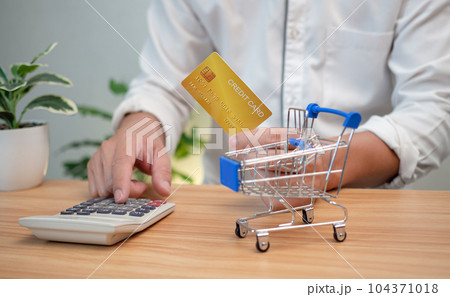 Man holding a credit card and pressing a calculator. Shopping concept. Cashless payment concept. Man holding a credit card and pressing a calculator. Shopping concept. Cashless payment concept. 104371018