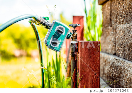 Garden water timer on a spigot with a splitter and hoses. 104371048
