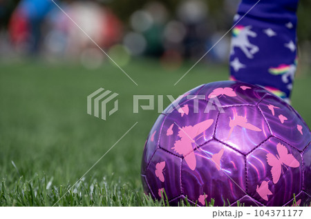 Selective focus on girls' soccer ball with a player on the grass field. Selective focus on girls' soccer ball with a player on the grass field. 104371177
