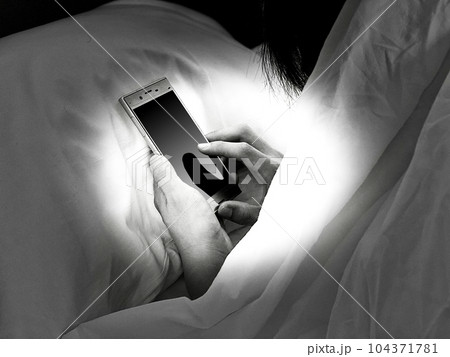 ベッドの中でスマホを見る人の手_モノクロ ベッドの中でスマホを見る人の手_モノクロ 104371781