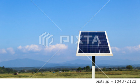Photovoltaic panel on blurred  field in background, concept for using solar cell panel to power water pump to agriculture area                                104372122