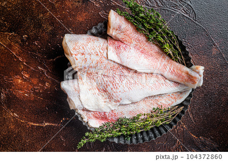 Raw ocean red perch fillet, Snapper fish with herbs. Dark background. Top view 104372860