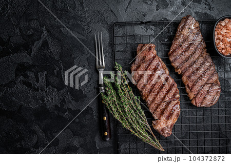 Grilled denver beef meat steak on a rack. Black background. Top view. Copy space Grilled denver beef meat steak on a rack. Black background. Top view. Copy space 104372872