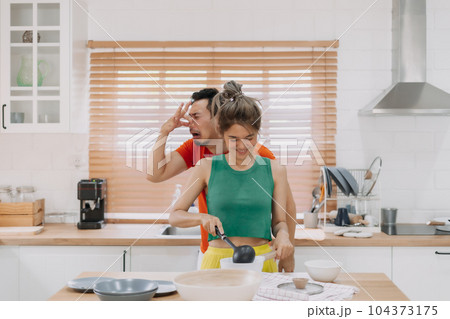 Husband feels worry behind his wife while she is cooking for him. Husband feels worry behind his wife while she is cooking for him. 104373175