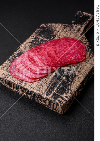 Delicious smoked salami sausage with salt, spices and herbs cut into slices Delicious smoked salami sausage with salt, spices and herbs cut into slices 104373691