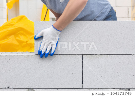 A worker lays a gas block on the wall. A worker lays a gas block on the wall. 104373749