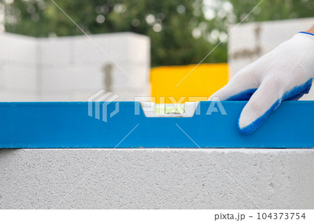 The worker sets the level on the wall of the gas block. The worker sets the level on the wall of the gas block. 104373754