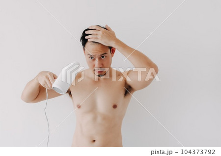 Man drying his hair after shower with hair dryer isolated on white background. 104373792