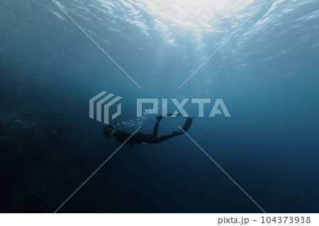 Free diver swimming into the deepness 104373938
