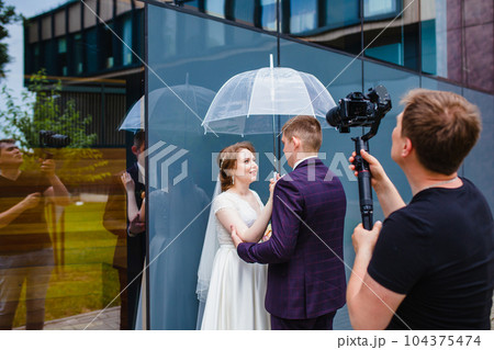 Professional wedding videographer shoots a movie with the newlyweds Professional wedding videographer shoots a movie with the newlyweds 104375474