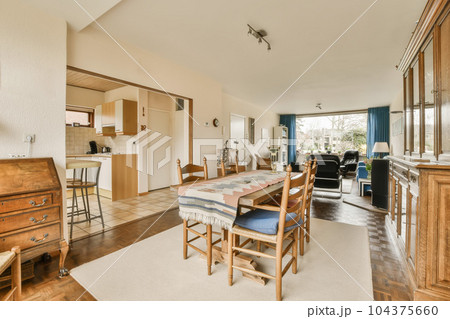 a kitchen and dining area in a house with wood flooring, white walls and wooden furniture on either sides 104375660