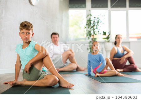 Boy performs asana lord of fish for yoga class with his family 104380603
