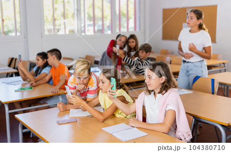 Schoolchildren use mobile phones at the lesson in classroom Schoolchildren use mobile phones at the lesson in classroom 104380710