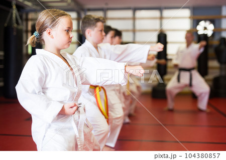 Girl practicing new moves during karate class 104380857