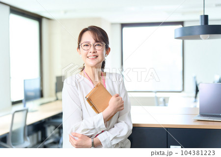 手帳を持ちオフィスに立つ女性 104381223