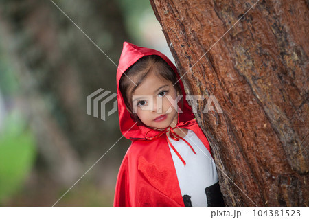 Sweet girl wearing a Little red riding hood costume. Real family having fun while using costumes of the Little red riding hood tale in Halloween. Sweet girl wearing a Little red riding hood costume. Real family having fun while using costumes of the Little red riding hood tale in Halloween. 104381523